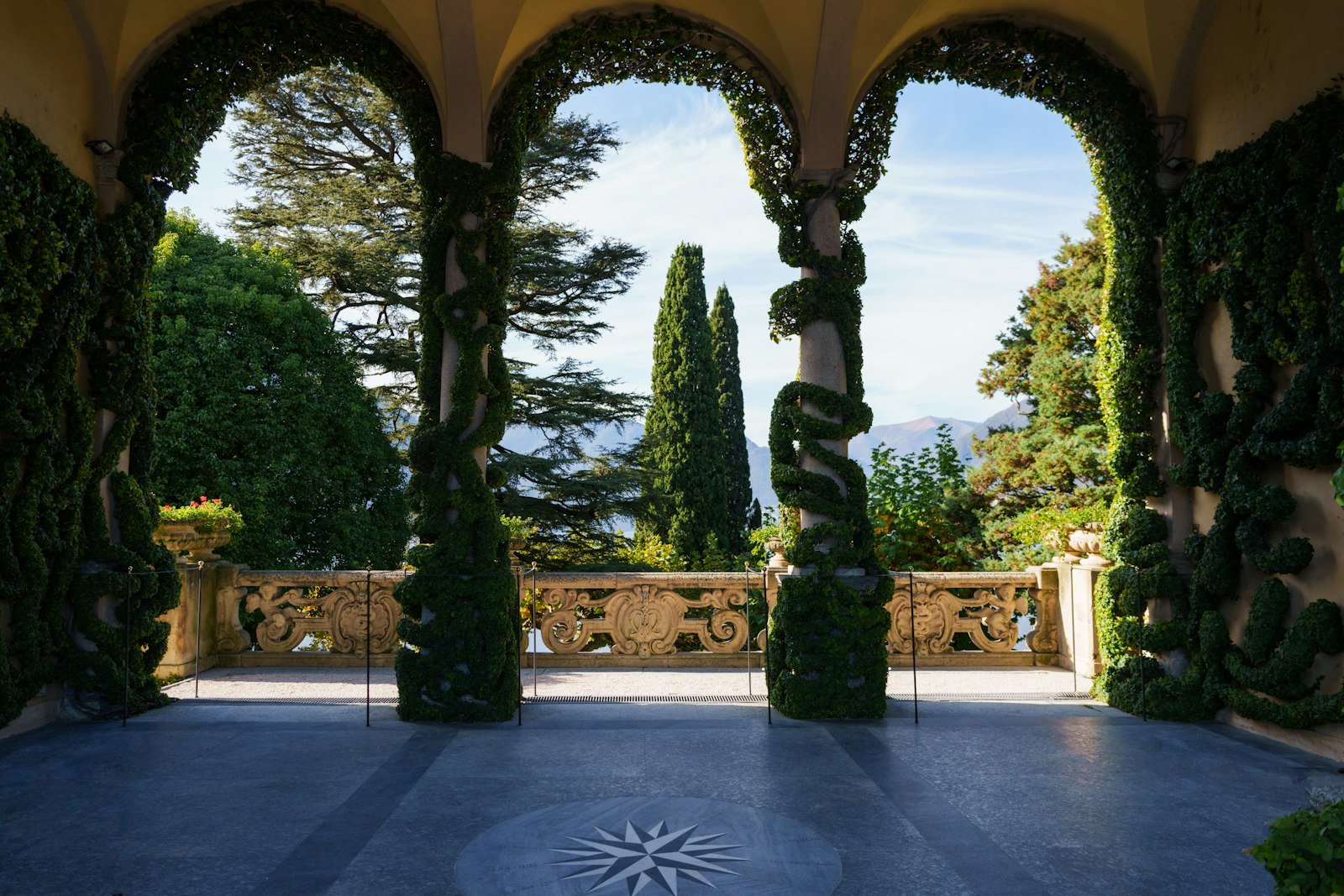 The arched loggia and topiary terrace of Villa del Balbianello overlooking Lake Como and the mountains